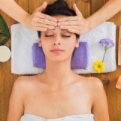 75186635 - head massage in spa. young woman in wellness center. professional cosmetologist make procedure to beautiful indian girl in beauty parlor. top view on wood with aroma salt and other treatments